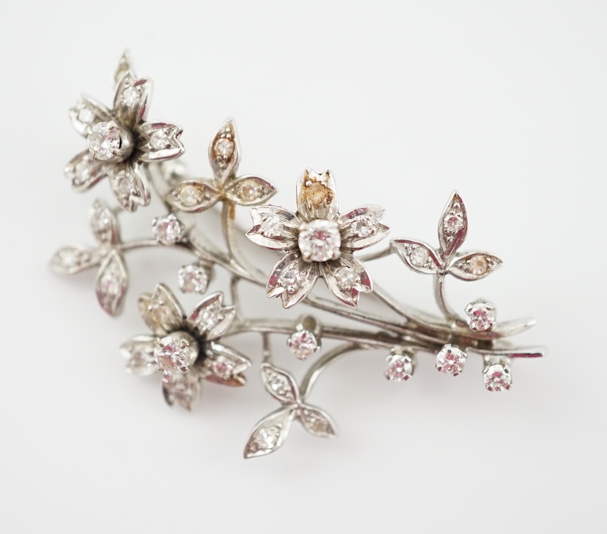 A 1960's 18ct white gold and diamond cluster set floral spray brooch